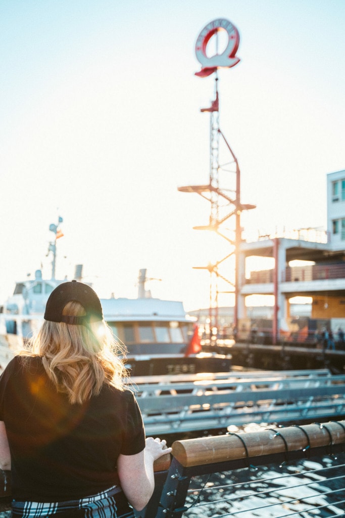 a woman stands at a railing looking over the sunny shipyards district on Vancouver's North Shore