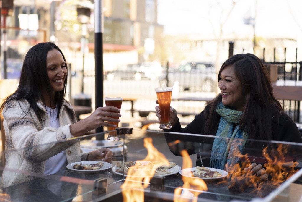two ladies enjoy craft beer and pizza at CrossRoads Brewing in Prince George on the heated patio