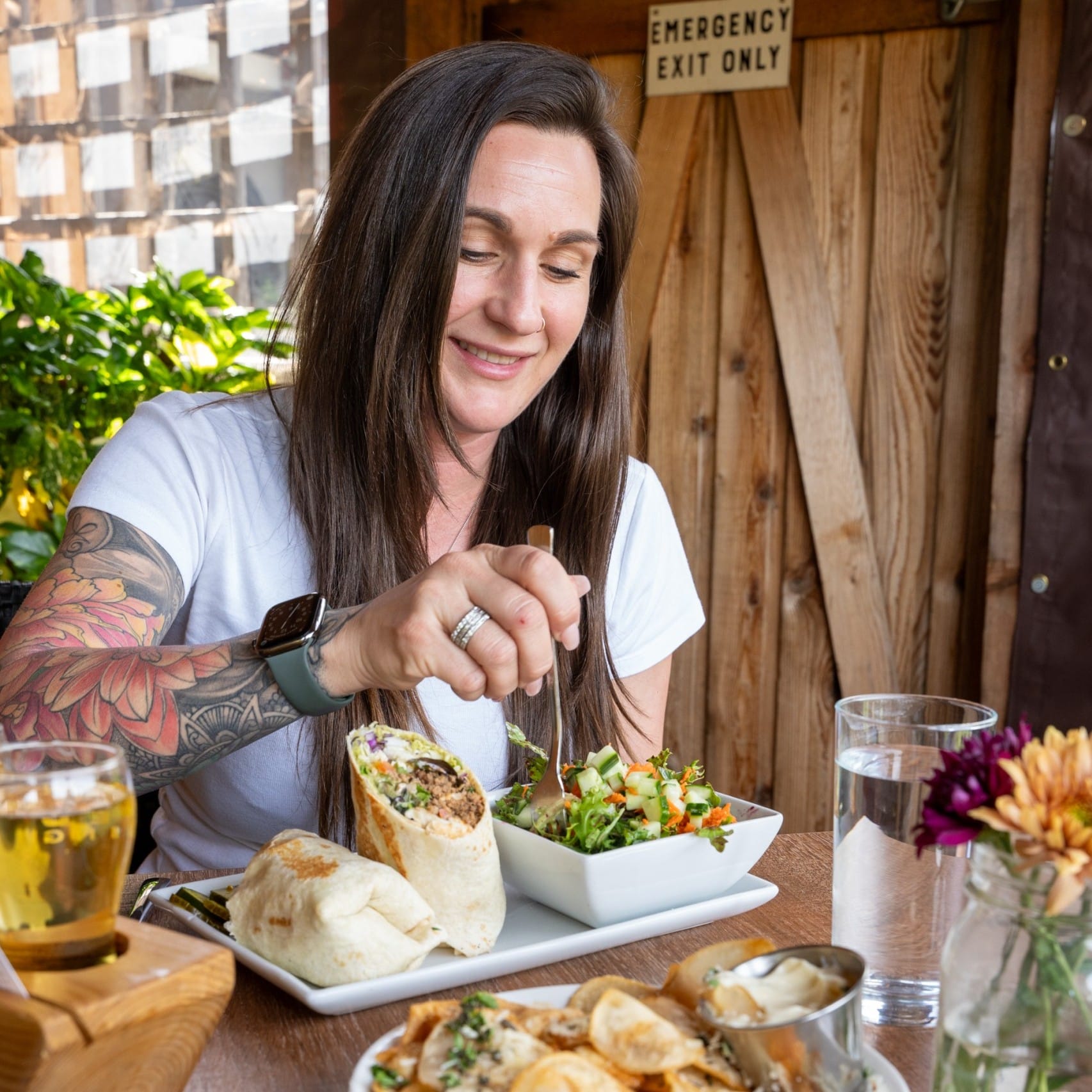 a woman digging in to a salad and wrap meal at Rusted Rake Brewing in Nanoose Bay, BC