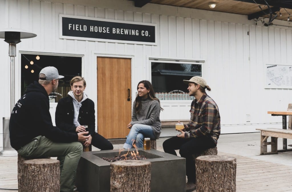 a group of people sit around a fire pit at the East Abbotsford Field House Brewing location, on the Fraser Valley Ale Trail
