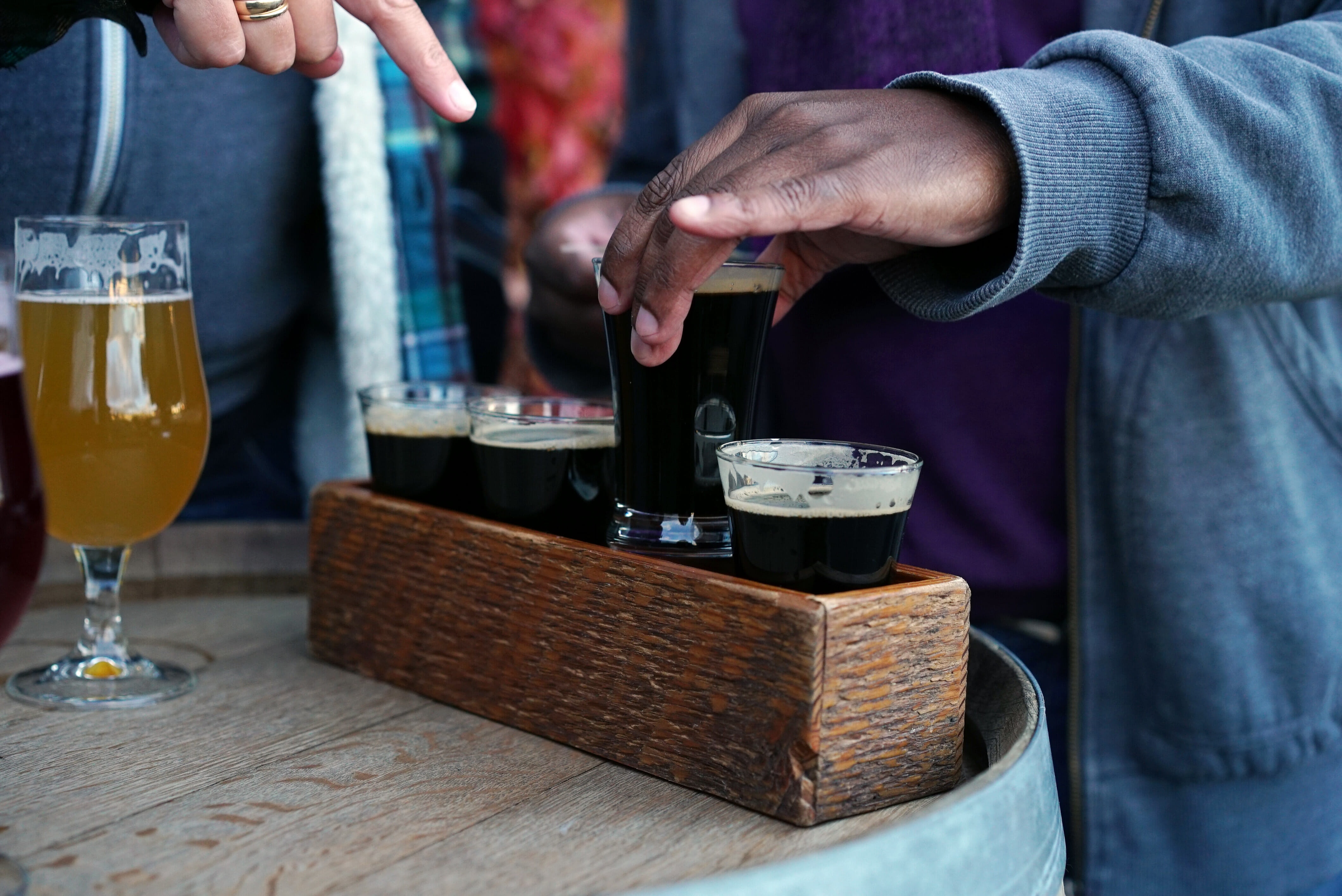 a hand reaching for a flight of craft beer at Strange Fellows Brewing in Vancouver, BC