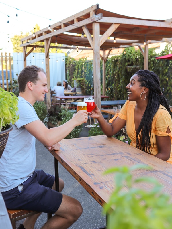 Two people cheers-ing on the patio at Luppolo Brewing in Vancouver, BC