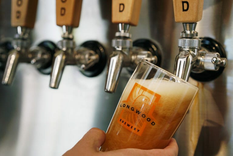 pouring a pint of craft beer into a branded glass at Longwood Brewery on Boxwood Road in Nanaimo, BC
