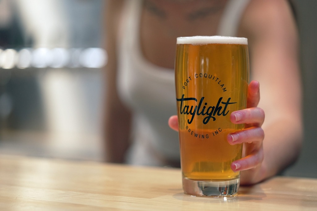 a staff member passes over a freshly poured pint of craft beer at Taylight Brewing in Port Coquitlam, BC