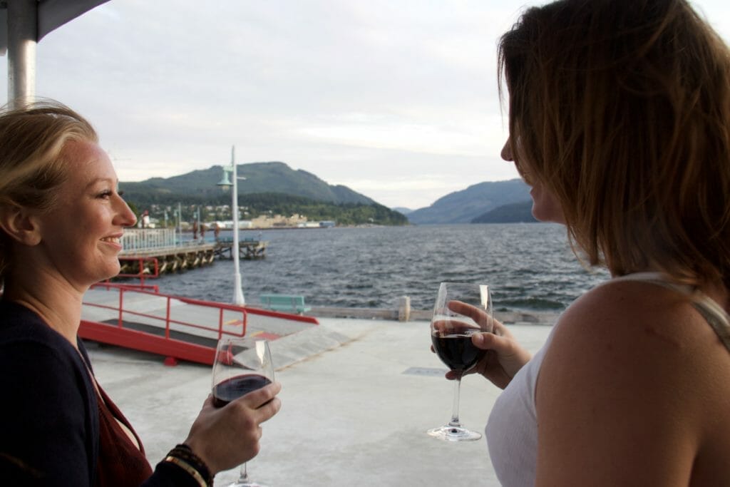 two women with beer glasses in hand looking out onto a dock at Swept Away Inn in Port Alberni 