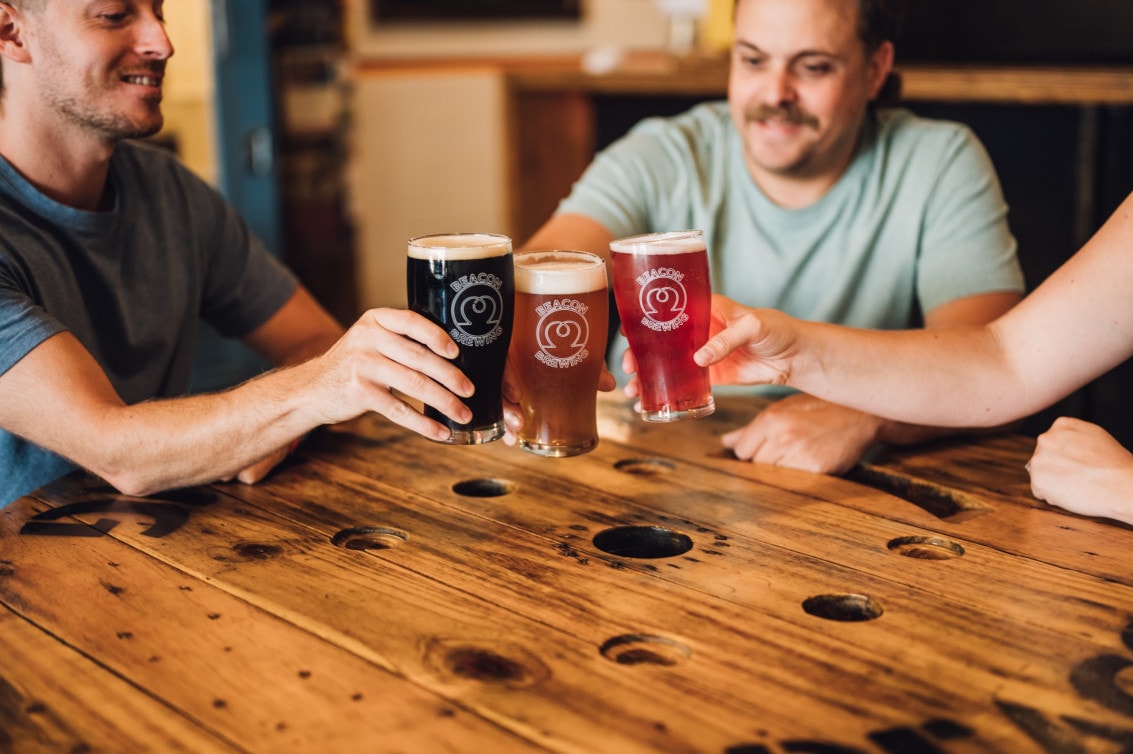 a group of people cheers glasses of craft beer at Beacon Brewing in Sidney, BC
