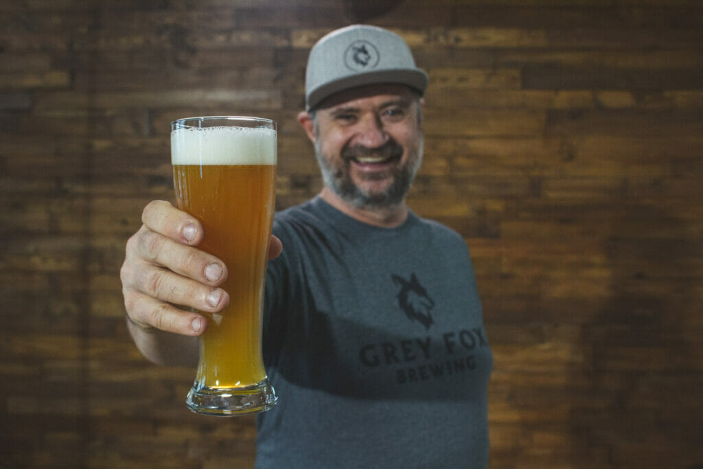 Chris, the owner, holding up a pint of beer at Grey Fox Brewing in Kelowna