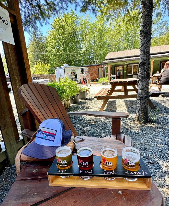 a ball cap sits next to a flight of craft beer on the shady patio at Bad Dog Brewing in Sooke, BC