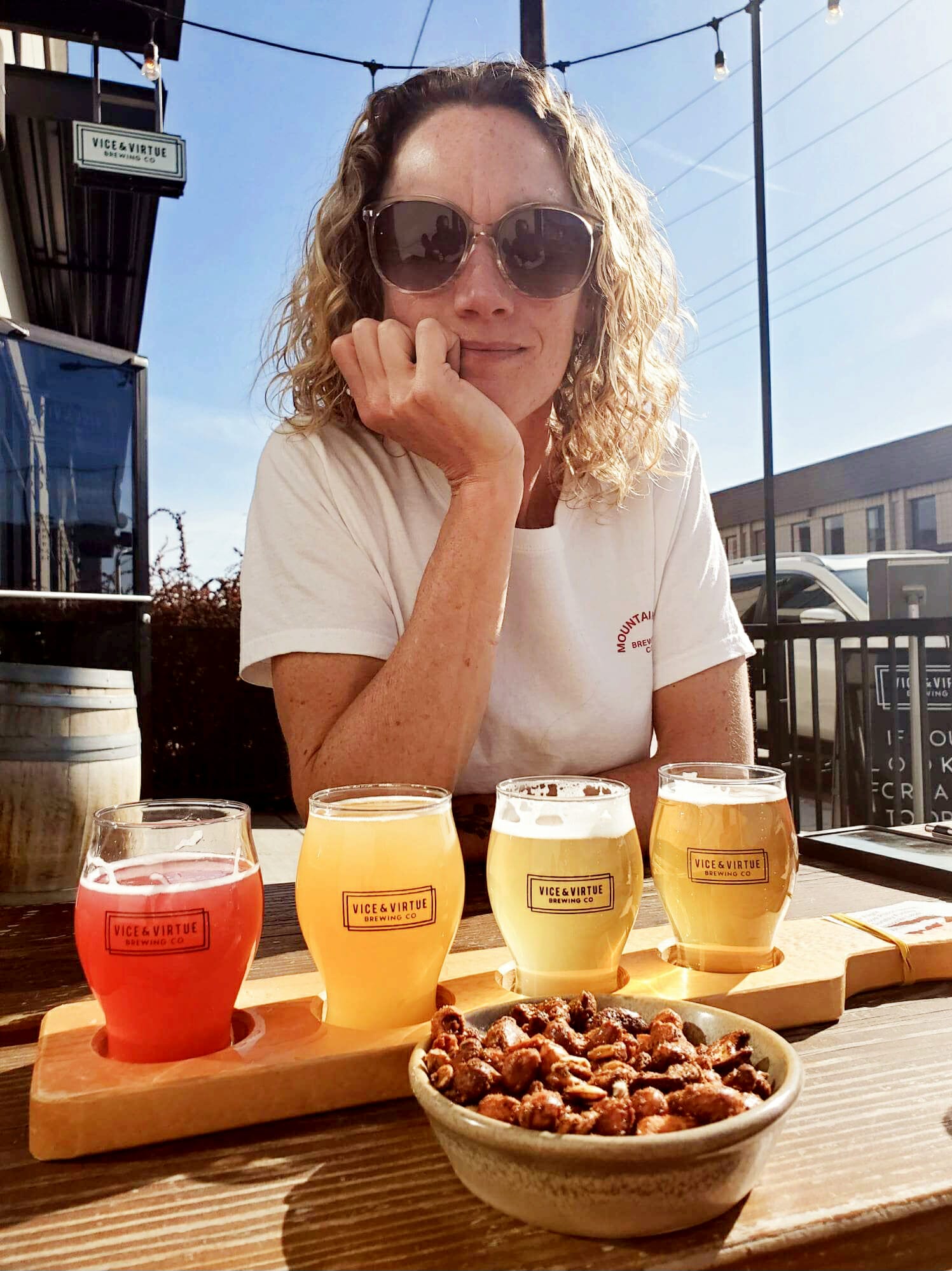 Hannah with a flight of beer and pretzels on the patio at Vice and Virtue Brewing in Kelowna, BC