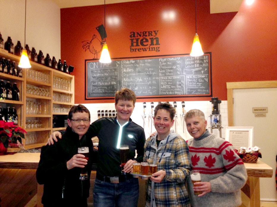 Four women smile with their beers at the counter of Angry Hen Brewing on opening day