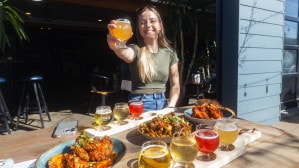 Marie with a spread of tasty food and craft beer flights on the sunny patio at Slackwater Brewing in Penticton