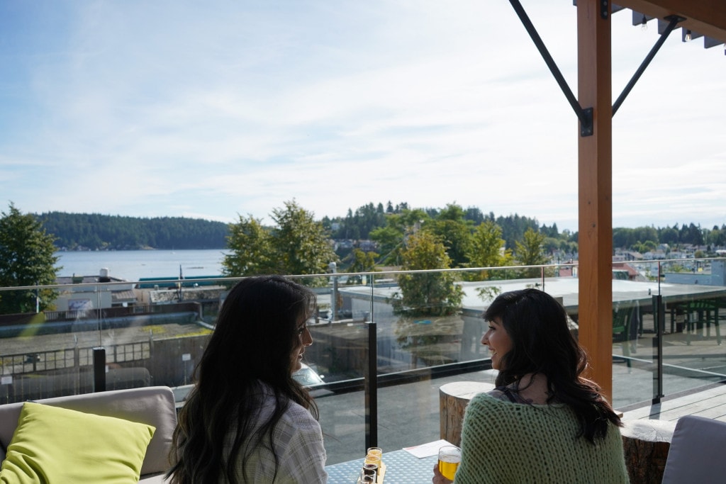 two women enjoying craft beers and ocean views on the rooftop patio of Tapworks Brewing Company in Gibsons on the Sunshine Coast, BC
