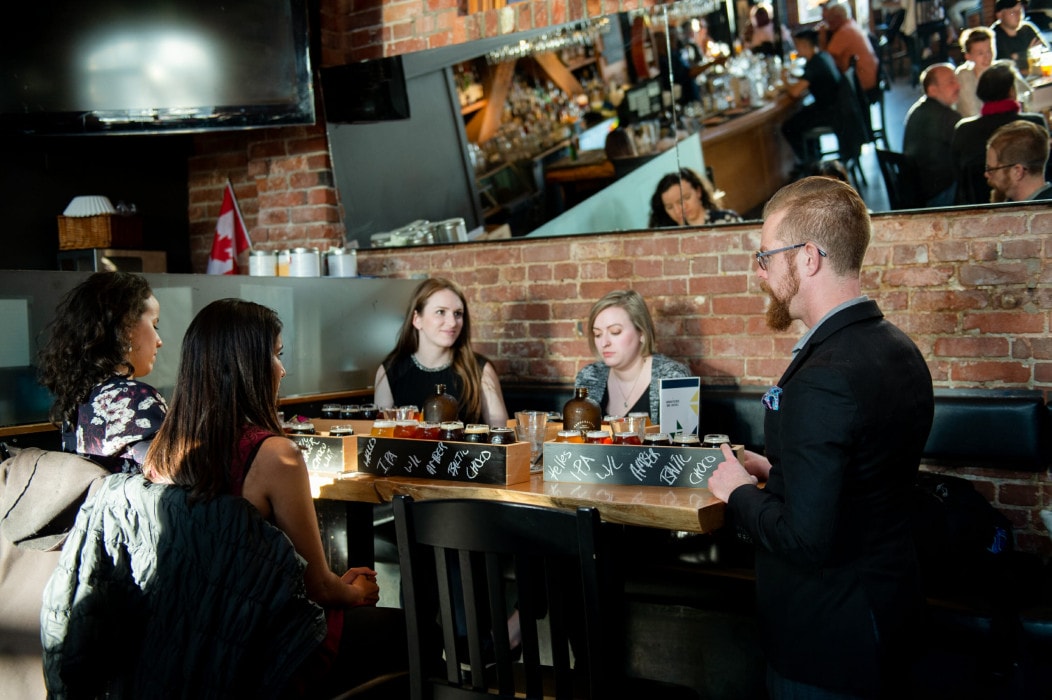 a server drops off flights of craft beer to a table of ladies