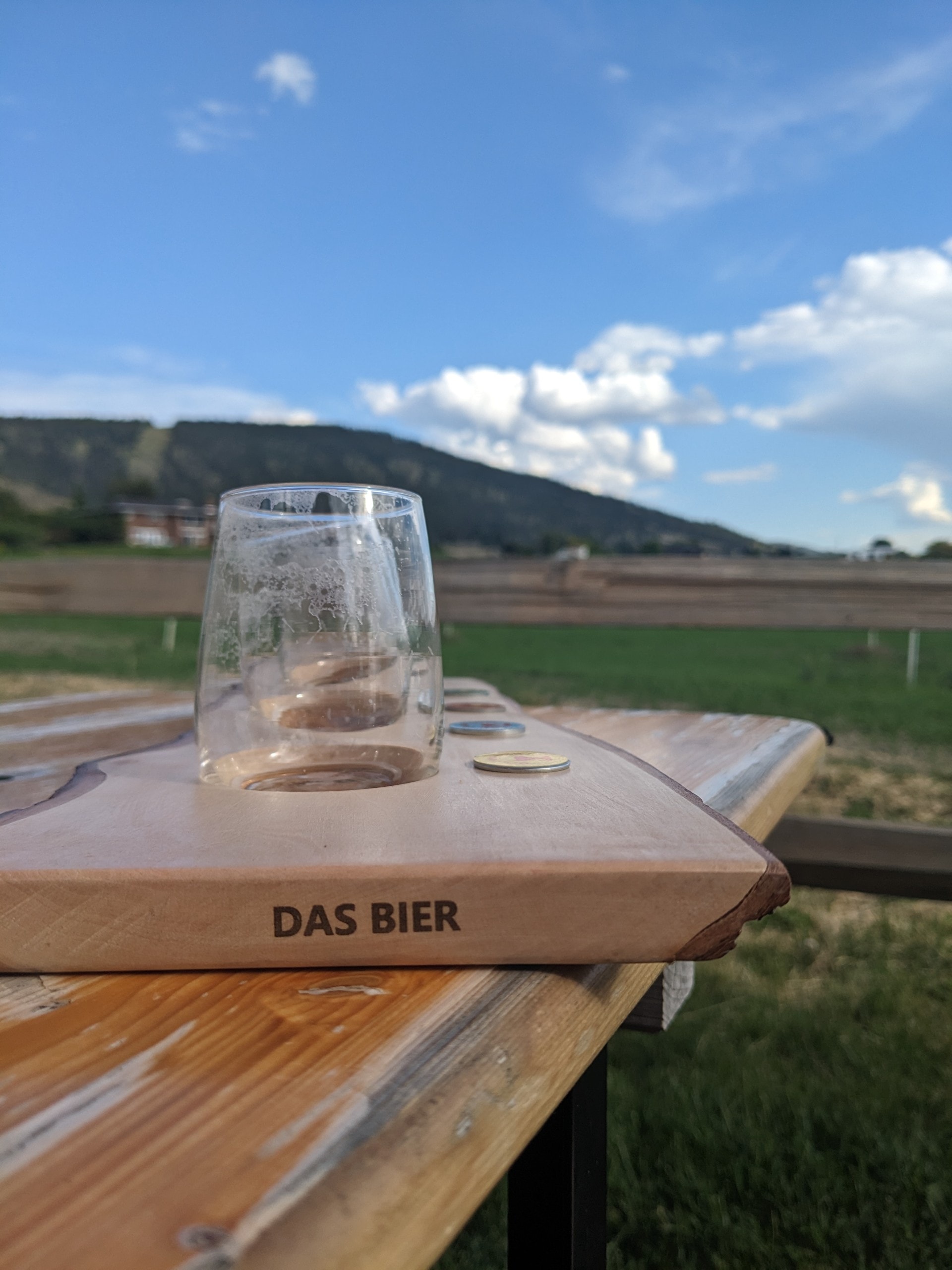 an empty flight of beer with green farm fields in the background at Abandoned Rail Brewing in Penticton, BC