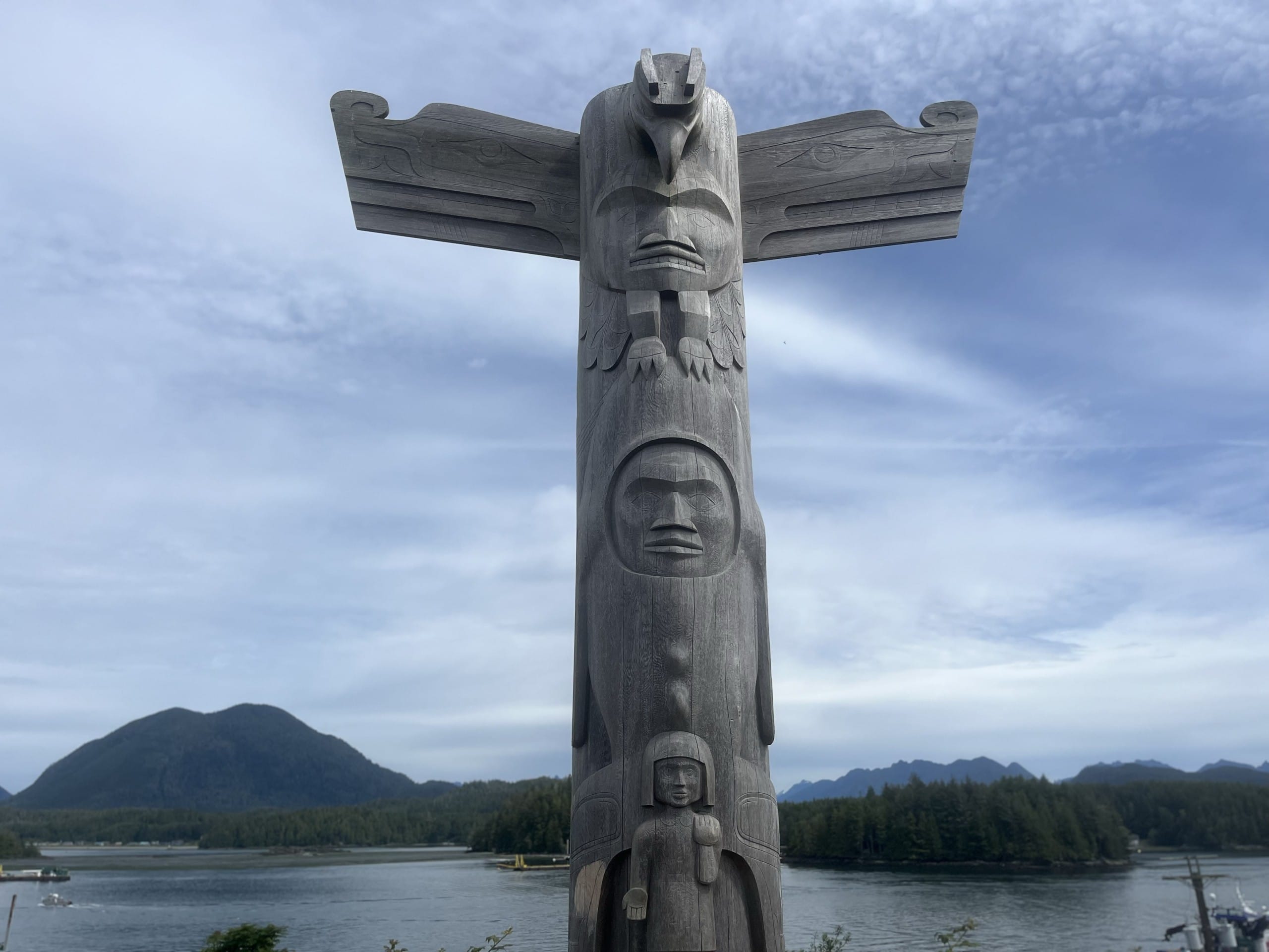 a totem pole stands near the ocean in Tofino, BC
