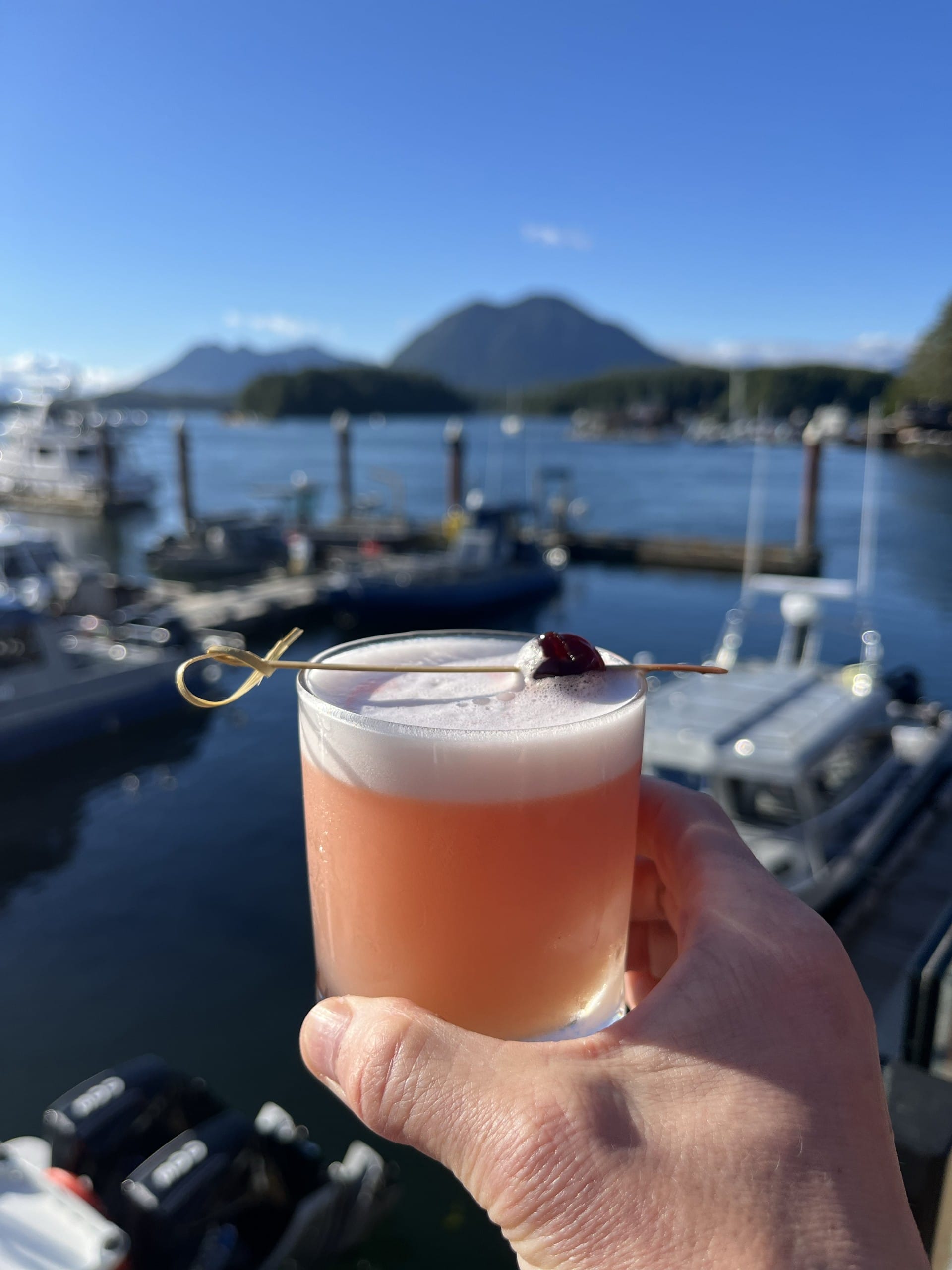 a cocktail from Shelter Restaurant in Tofino, BC, with harbour views in the background