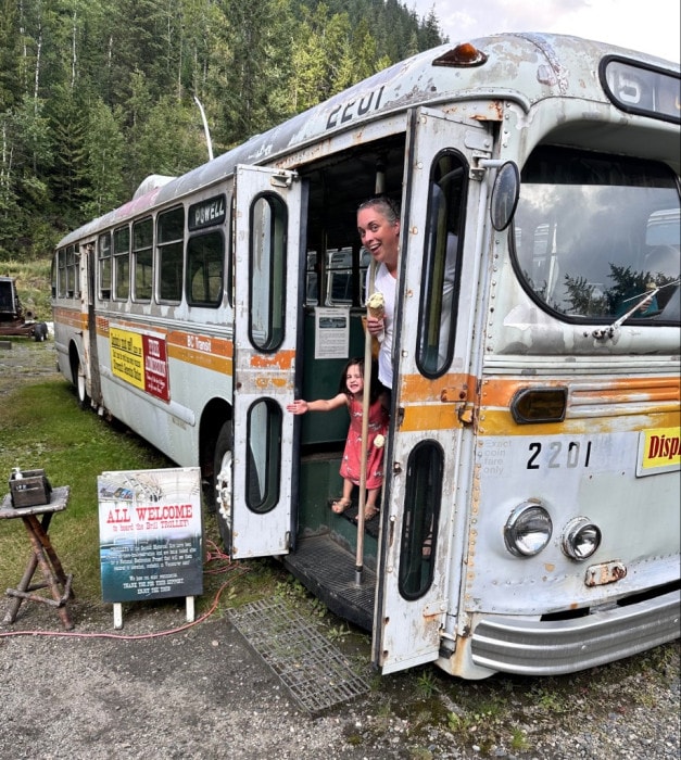Author Rob Mangelsdorf's wife and daughter look out of the doors of a defunct electric trolly bus in the ghost town of Sandon, BC