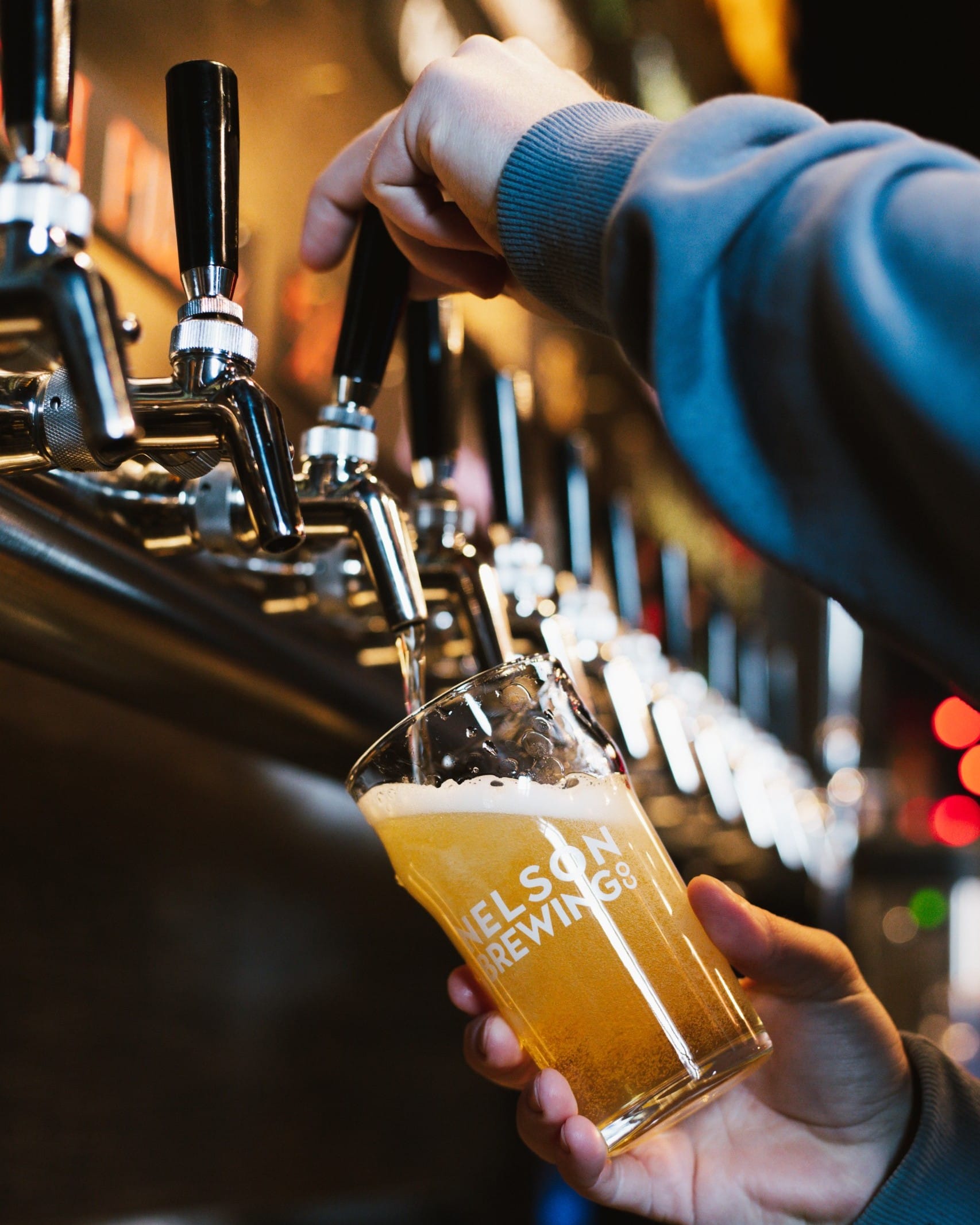a staff member pours a pint of craft beer at Nelson Brewing Co, in Nelson, BC