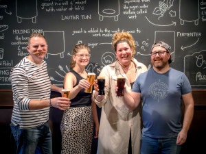 The managing partners at the Noble Pig Brewhouse pose with pints raised. L to r: Jared Summers (executive chef), Sara Hanrahan (restaurant manager), Meaghan Summers (operating manager), and Nick Murphy (head brewer)