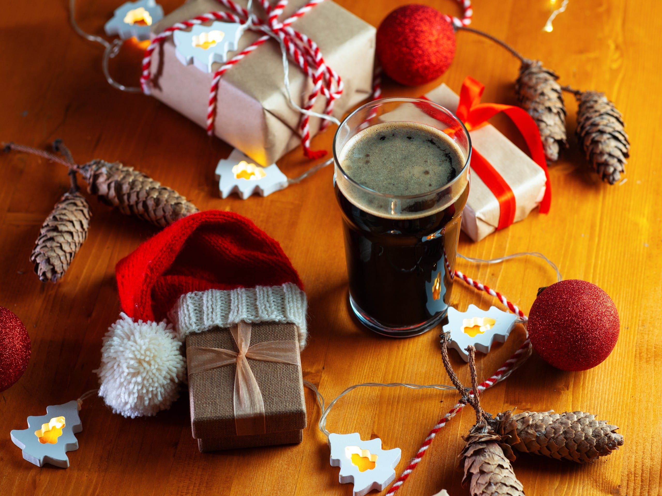 a pint of stout sits on a table among chrismtas decorations and presents