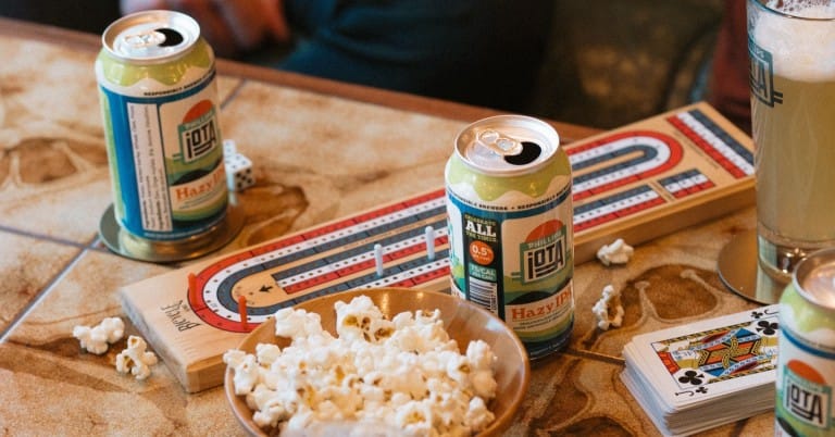 a table full of card games, popcorn and non-alcoholic iOTA beer from Phillips Brewing & Malting in Victoria, BC