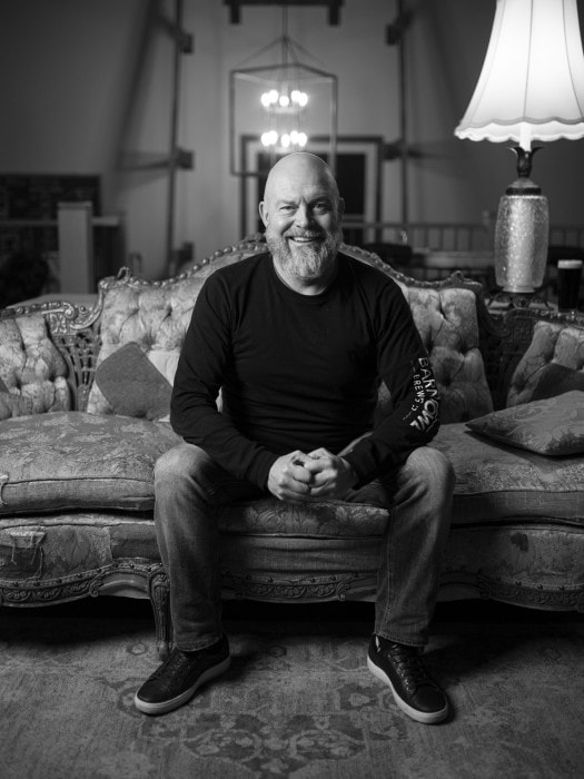 Gary Brucker from Barn Owl Brewing in Kelowna smiles for the camera from a vintage couch in the brewery's tasting room