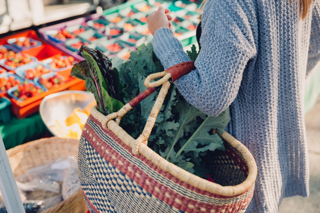 a person shopping with a large reusable woven basket at the Kamloops Regional Farmers' Market