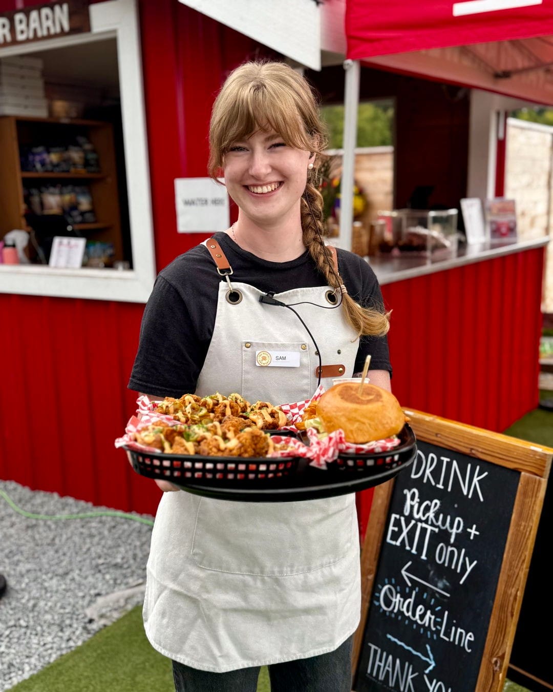 a staff member holds a tray loaded with burgers and cauliflower bites