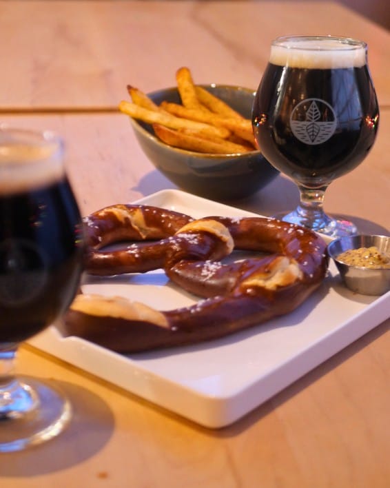 a glass of craft beer, warm pretzel and fries at Connector Brewing in West Kelowna, BC