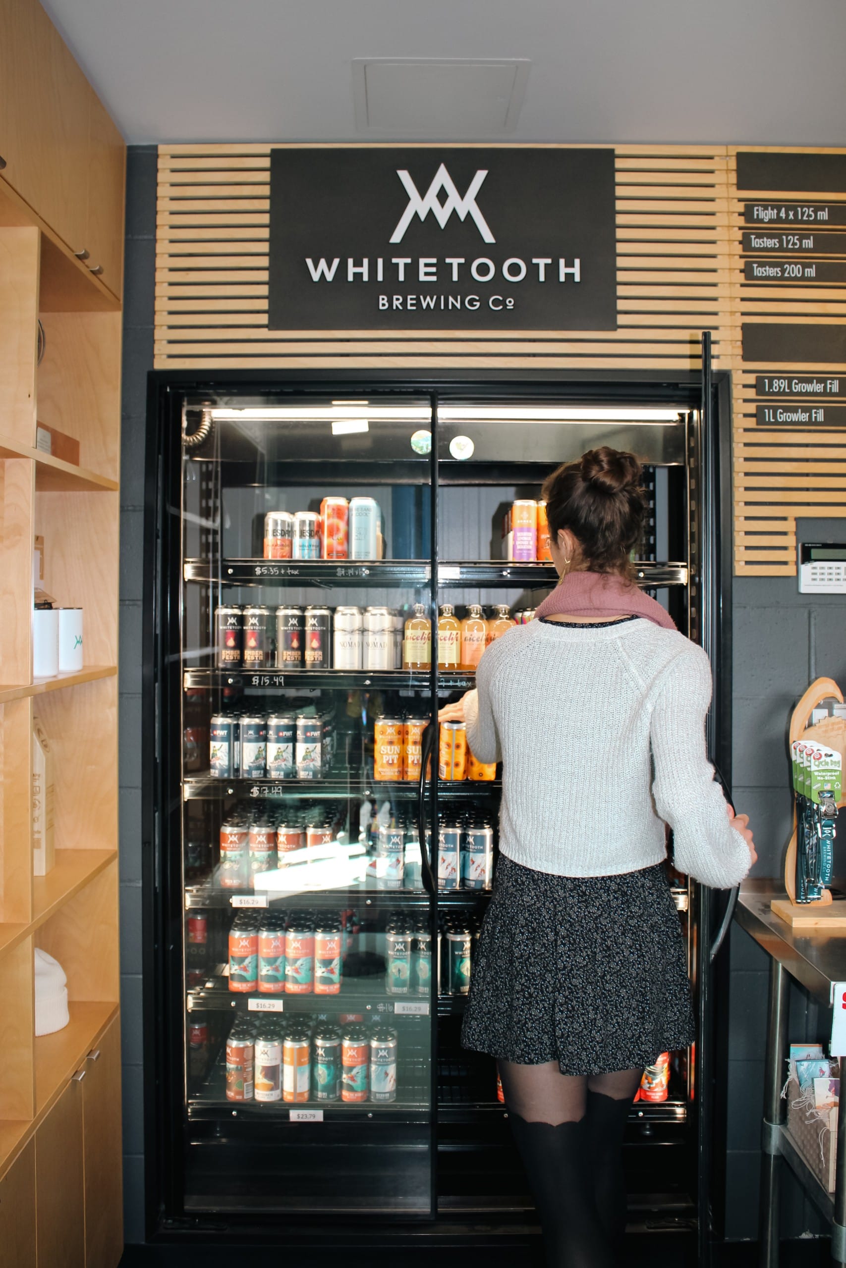 a person reaches for a four pack of beer to go in the cooler at Whitetooth Brewing in Golden, BC