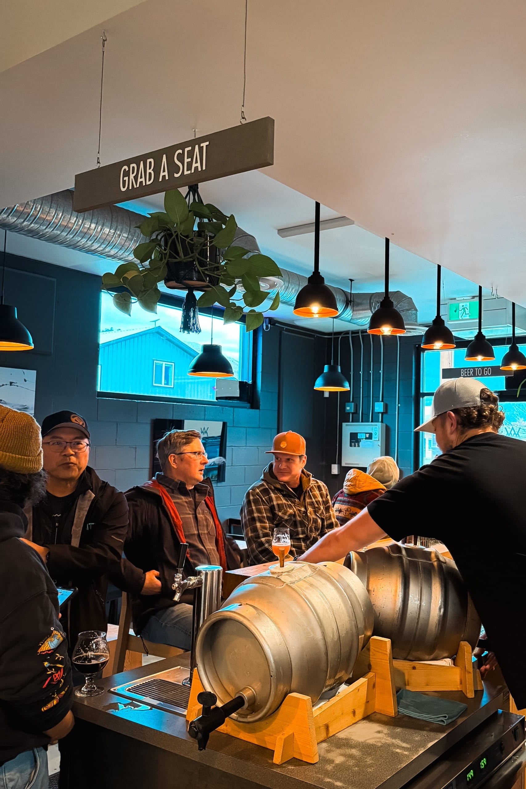 a group of people at the bar, where two casks are being poured from at Whitetooth Brewing in Golden, BC